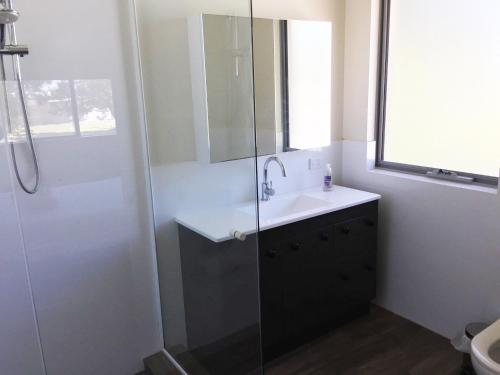 a bathroom with a sink and a glass shower at Blue Sky Apartment in Jurien Bay