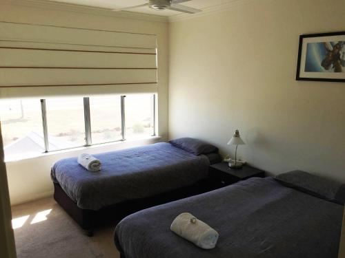 Blue Sky Apartment في جوريين باي: غرفة نوم بسريرين ونافذة مطلة