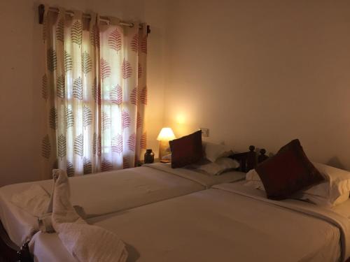 Duas camas brancas num quarto com uma janela em Kovilakam Lakeside Villa em Alappuzha