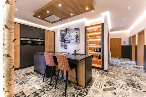 una cucina con isola e sgabelli da bar di Kitz Residenz by Alpin Rentals - 8 Apartments a Kaprun