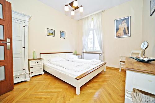 a bedroom with a large white bed and a wooden floor at Red Apartment Czyżewskiego by Grand Apartments in Sopot