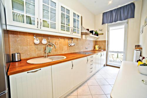 a kitchen with white cabinets and a sink at Red Apartment Czyżewskiego by Grand Apartments in Sopot