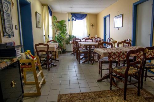 a restaurant with tables and chairs in a room at Hôtel de Bâle in Bantzenheim