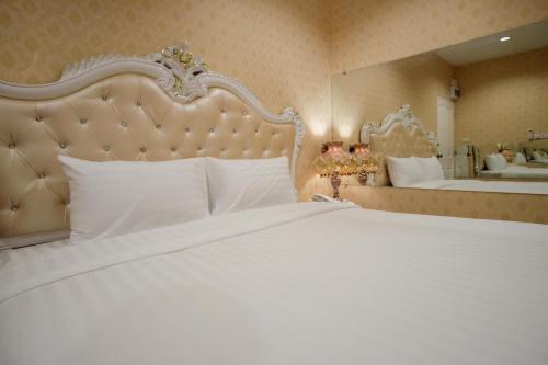 een slaapkamer met een groot wit bed en een spiegel bij The O-Zone Airport Inn in Ban Khlong Prawet