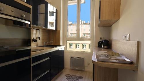 une petite cuisine avec des armoires noires et une fenêtre dans l'établissement Apartment Port, à Nice