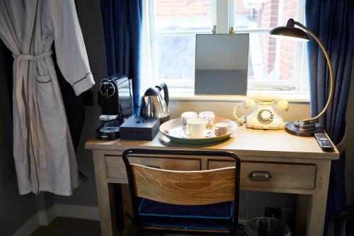 a wooden desk with a lamp and a tea set on it at Wykeham Arms in Winchester