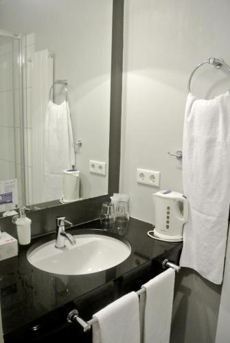 a bathroom with a sink and a mirror and towels at Town Hotel Wiesbaden - kleines Privathotel in Bestlage in Wiesbaden