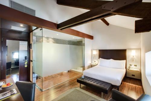a hotel room with a bed and a glass wall at Hotel Sercotel Ciutat D'Alcoi in Alcoy