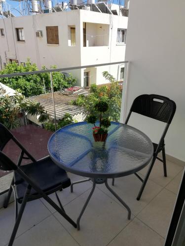 a glass table and two chairs on a balcony at Chicos Studios in Ayia Napa