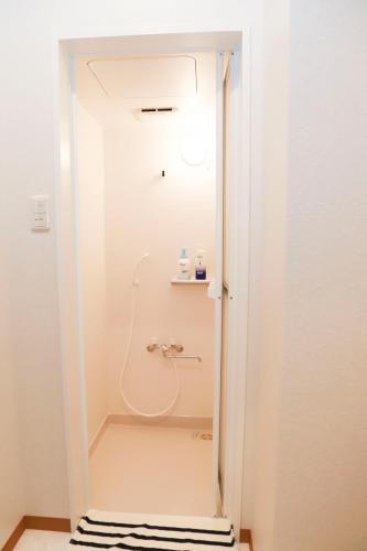 a shower in a white bathroom with a sink at Guest House En in Nara