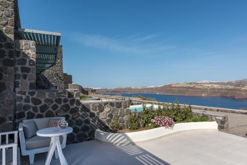 a patio with a table and a chair and a view at Elements of Caldera Suites in Akrotiri