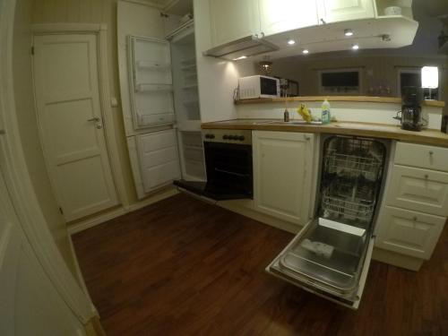 a kitchen with white cabinets and an open dishwasher at Apartment near the airport in Tromsø