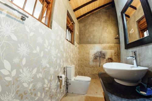 a bathroom with a sink and a toilet at Thambili Cabanas in Hikkaduwa
