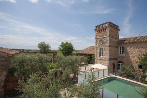 un bâtiment avec une tour de l'horloge et une piscine dans l'établissement Domaine Sainte Suzanne, à Puimisson