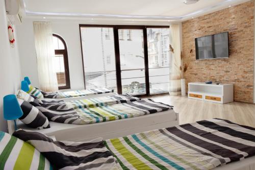 two beds in a bedroom with a tv on a brick wall at Ana's Apartments in Ohrid