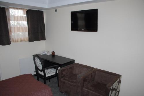 a bedroom with a desk and a couch and a television at B&B Rose in Vranje