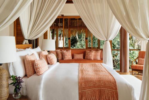 a bedroom with a large white bed with curtains at NIHI Sumba - 50 Best Hotels of the World in Watukarere