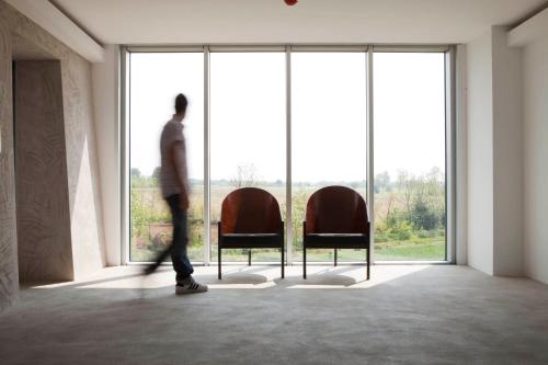 a man walking through a room with two chairs at Aiden by Best Western JHD Dunant Hotel in Castiglione delle Stiviere