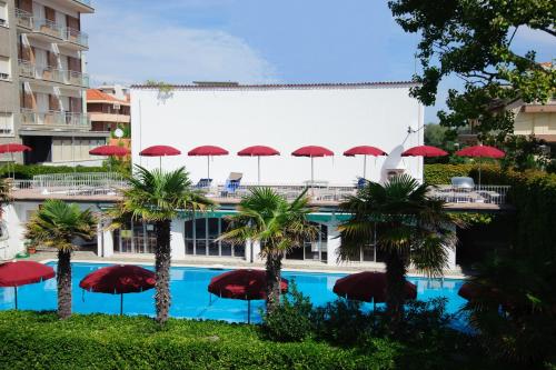 une piscine avec des parasols rouges en face d'un bâtiment dans l'établissement Hotel Nautic B&B, à Bellaria-Igea Marina