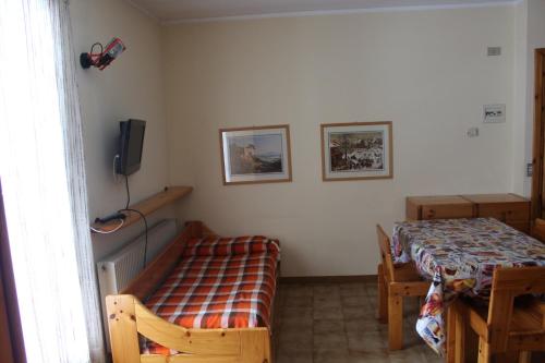 a bedroom with a bed and a table and a television at Residence Raethia tra Bormio e Livigno in Valdidentro