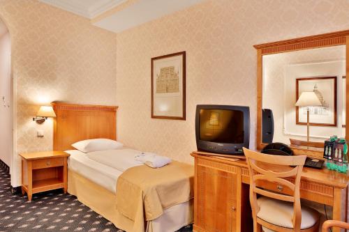 a hotel room with a bed and a tv at Belvedere Wellness Hotel in Mariánské Lázně