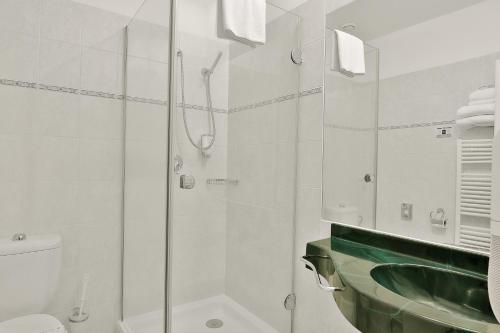 a bathroom with a shower and a sink and a toilet at Belvedere Wellness Hotel in Mariánské Lázně