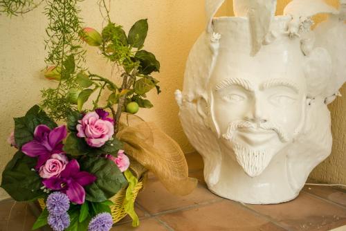 Una statua di un volto vicino a un mazzo di fiori di La Residenza Dei Mori - Taormina Holidays a Taormina