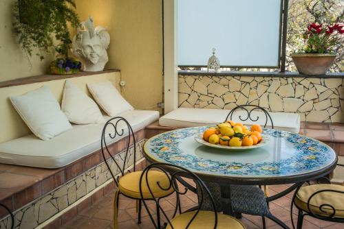 un tavolo con sedie e un cesto di frutta. di La Residenza Dei Mori - Taormina Holidays a Taormina