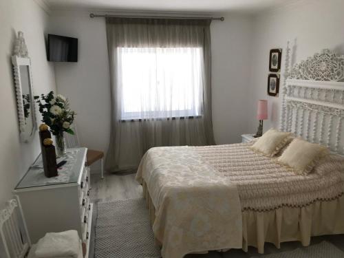 a white bedroom with a bed and a window at Vivenda Azevedo in Nazaré
