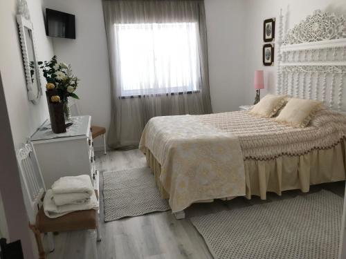 a white bedroom with a bed and a window at Vivenda Azevedo in Nazaré