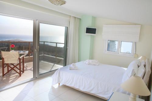 a bedroom with a bed and a balcony with the ocean at Blue Luxury Maison in Possidi