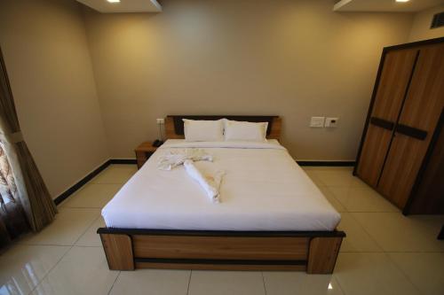 a bedroom with a bed with white sheets and pillows at Hotel Golden Gateway in Vellore