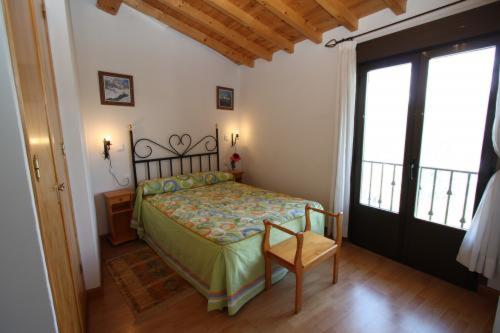 1 dormitorio con 1 cama, 1 silla y 1 ventana en Casa Rural el Huerto, en Solana de Ávila