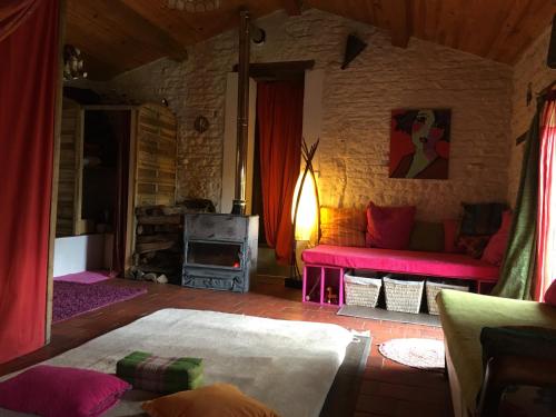a living room with a red couch and a fireplace at Dormir Ben Aise in Maillezais