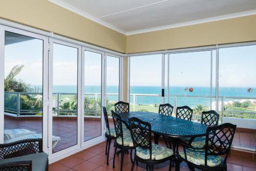 a dining room with a table and chairs and the ocean at Long Island 42 in Ballito