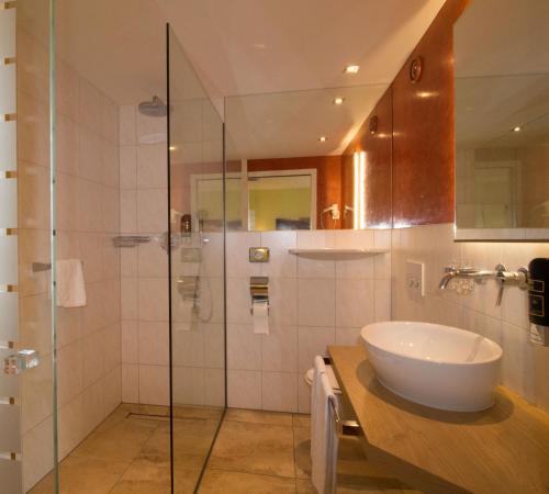 a bathroom with a sink and a glass shower at Hotel Munde in Telfs