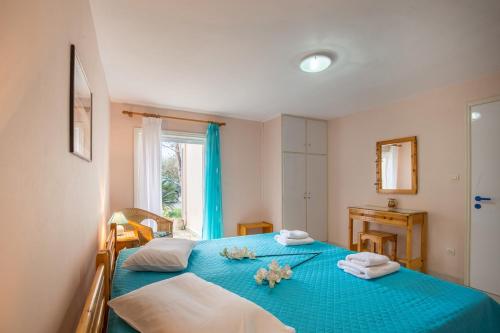 a bedroom with a blue bed with towels and a window at Ormos Drepanou Apartments in Lygia