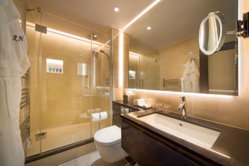 y baño con lavabo, aseo y espejo. en The Rathbone Hotel, Fitzrovia, en Londres