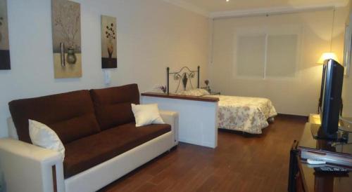ein Wohnzimmer mit einem Sofa und einem Bett in der Unterkunft Hostal los Dos Naranjos in El Arahal