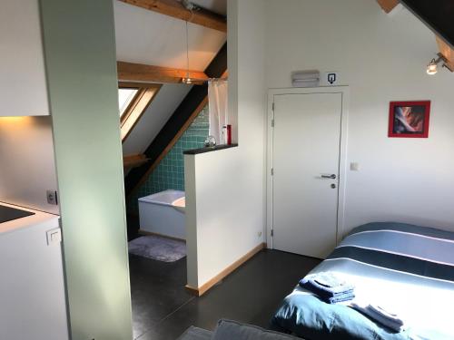 a small bedroom with a bed and a staircase at Rap 'n Holiday Home in Sint-Denijs-Westrem