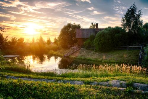 una puesta de sol sobre un estanque con un granero y una casa en HOT SPRINGS, en Suzdal