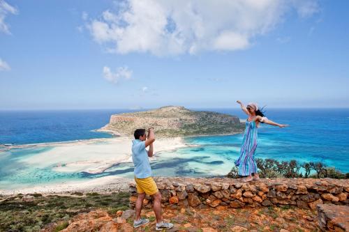 a man and woman standing on top of a rock wall overlooking a beach at Mrs Chryssana Beach Hotel in Kolymvari