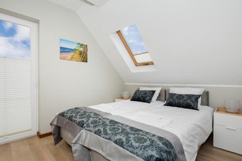 a white bedroom with a bed and a window at Holiday House Nemo by Renters in Międzywodzie