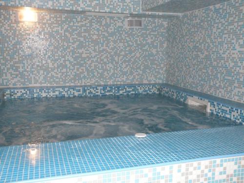 a bathroom with a large tub with blue tiles at Belveder Holiday Club Private in Bansko