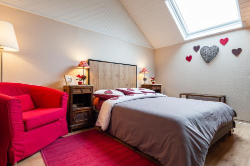 a bedroom with a bed and a red chair at La Rose Trémière in Wintzenheim-Kochersberg