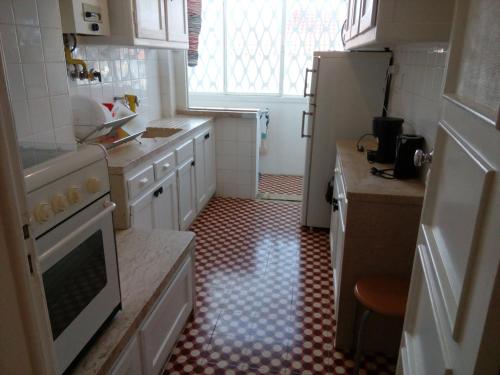 a kitchen with white cabinets and a red and white tile floor at Voyage 63 in Lisbon