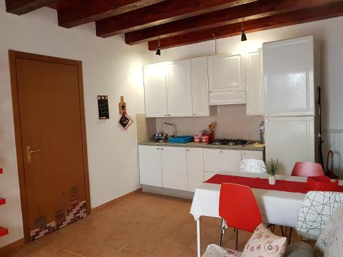 a kitchen with white cabinets and a table with red chairs at Appartamento Aretusa in Syracuse
