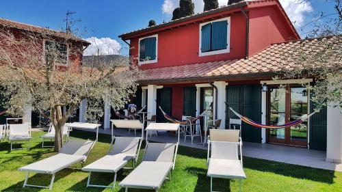 a patio with white chairs and tables and a red house at Hotel La Posta di Torrenova in Orbetello