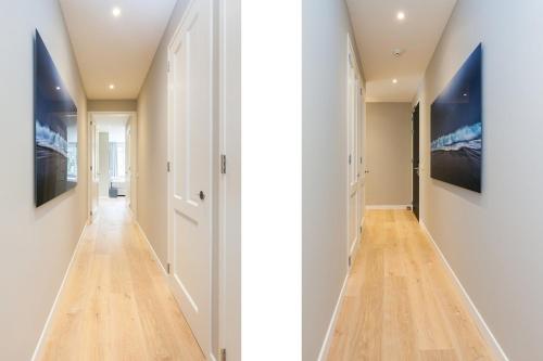 a hallway with white walls and wood floors and paintings on the walls at Mezger Lodges in Domburg