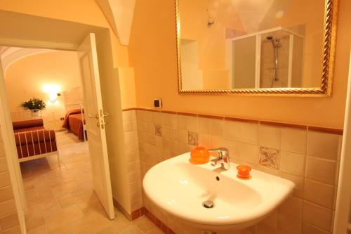 W łazience znajduje się biała umywalka i lustro. w obiekcie B&B Ippocastano w mieście Casarano